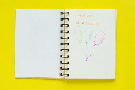 Top view of notebook with happy birthday greeting and three drawed balloons with copy space. Celebration consept