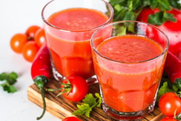 Tomato vegetable juice in glass on white.