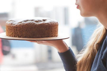A woman, a waiter or a baker holds an appetizing freshly baked brown pie peeled with powdered sugar. Cropped photo