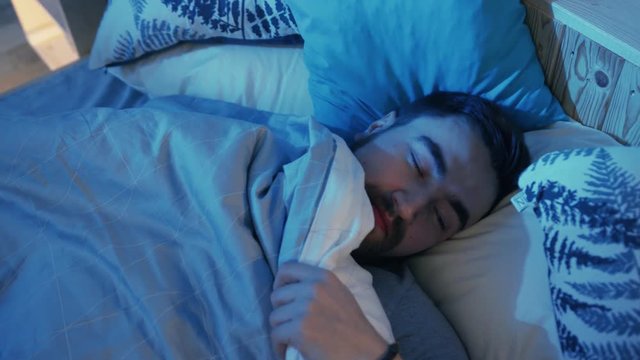 Young man waking up at night. Guy squinting. Indoors. Night time. Darkness, dream, evening, handsome, health, home, illumination, interior, lay, person, pillow, relax, room