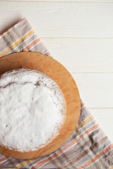 delicious tart sprinkled with white powdered sugar or cream. Photo from above. The pie is located on a stand with a tablecloth on a white table
