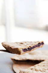 A stylish photo of a piece of a thin pie with fruit filling. Brown cake with berries.