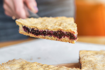 A stylish photo of a piece of a thin pie with fruit filling. Brown cake with berries.