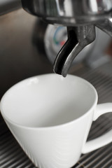 empty white cup set in coffee machine awaits hot freshly brewed coffee