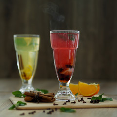 two glasses with colored hot drinks from which steam comes. winter hot seasonal drinks
