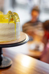 bright juicy white cake with yellow frosting and decorations as physalis, stands on a base with a high leg in the interior cafe