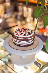 Cake from many thin brown pancakes in the form of pancakes stuffed with white cream and stopped with berries and fruits