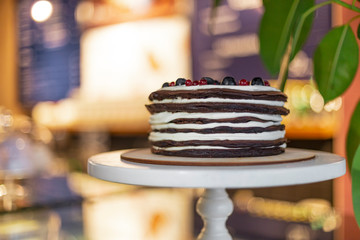 Cake from many thin brown pancakes in the form of pancakes stuffed with white cream and stopped with berries and fruits