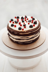 Cake from many thin brown pancakes in the form of pancakes stuffed with white cream and stopped with berries and fruits
