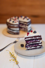 A piece of appetizing cake consisting of many brown cakes and white cream standing next to a big cake