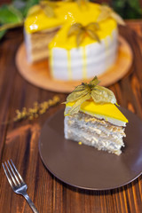 delicious and appetizing piece of high cake with yellow fruits on a plate on the background of a cake