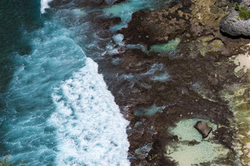 Epic aerial view of blue ocean waves crashing into rocky coast
