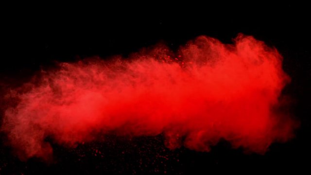Super slowmotion shot of red powder explosion isolated on black background.