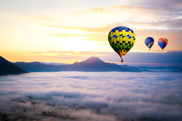 Sunrise scenery gold sky with hot air balloon flying over valley hill mountain and sea fog morning day in The north part of Thailand.