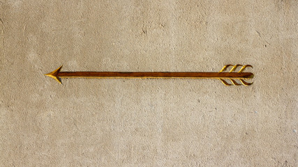 Golden Arrow carved in white marble pointing to the left