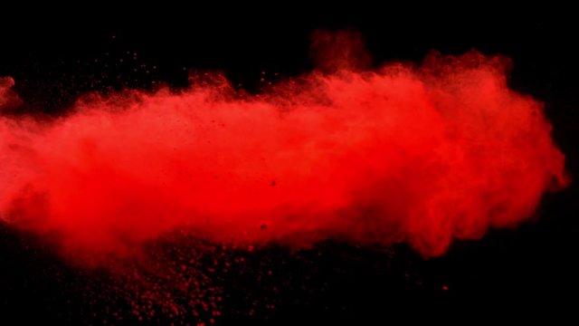 Super slowmotion shot of red powder explosion isolated on black background.