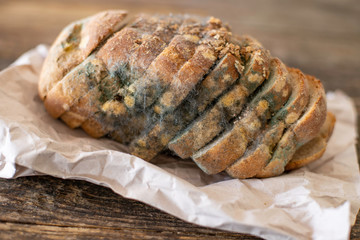 Moldy bread on the wooden rustic table , scarcity