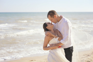Young adult wedding couple kissing near the sea