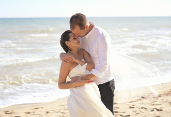 The bride and groom stand leaning each other against of a sea