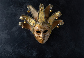 Venetian mask on a black background. Gilded mask on a stone black wall background.