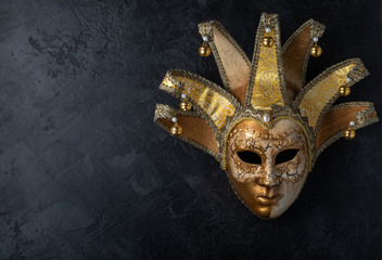 Venetian mask on a black background. Gilded mask on a stone black wall background. © SOLOTU