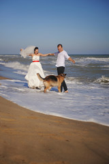 Newlywed couple celebrating marriage outdoors with their german shepherd dog