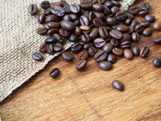 Close up of roasted coffee beans on sackcloth, wooden background