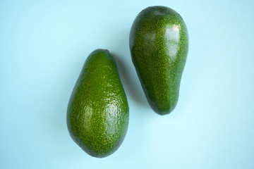  two ripe green beautiful avocados on a blue background are centered