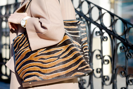Bag in leopard print close-up. large shopping leather handbag in female hands. Woman walking in the city. Girl in a beige coat.