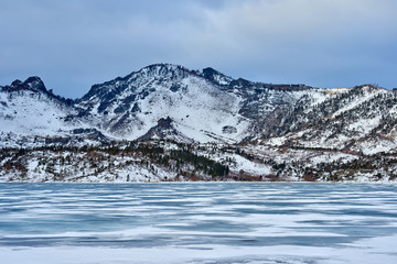 Lake Zhasybay. Winter morning. Bayanaul National Park. Kazakhstan.  Lake Zhasybay in winter. Beautiful rocky island on a background of cloudy sky and smooth ice with cracks. Bayanaul National Park. Ka