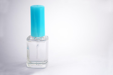 Closed bottle of clear nail polish for manicure on a light background. Clear transparent nail polish bottle with blue screw cap. Clear nail polish with copy space, moke up. Manicure concept.