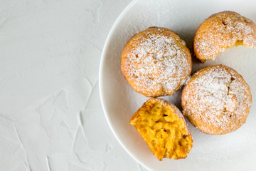 homemade orange pumpkin muffins with powdered sugar on a white plate. copy space. the view from the top.