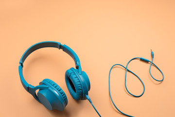 Photo of stylish modern blue cyan headphones over beige background