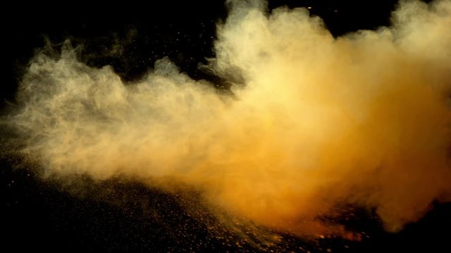 Super slowmotion shot of yellow powder explosion isolated on black background.