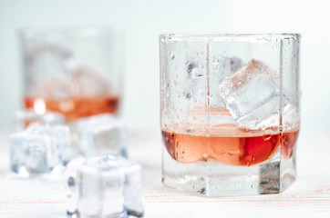 Glasses of grapefruit / orange juice with ice cubes, white background, wooden backdrop