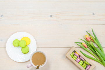 Tulips  with macaroons and cup of coffee  on brown wooden background. Backdrop with empty space for text