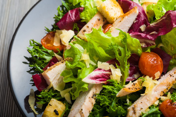 Healthy chicken salad with lettuce, grilled tomato, croutons, shredded cheese and grilled chicken