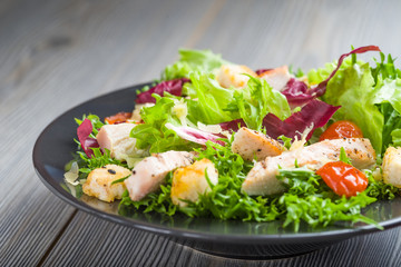 Healthy chicken salad with lettuce, grilled tomato, croutons, shredded cheese and grilled chicken