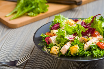 Healthy chicken salad with lettuce, grilled tomato, croutons, shredded cheese and grilled chicken