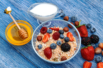Muesli Breakfast with oatmeal, milk and honey. Closeup of a crunchy granola with a bunch of fresh berries, sunflower seeds and hazelnuts. top view. Healthy diet. proper diet.