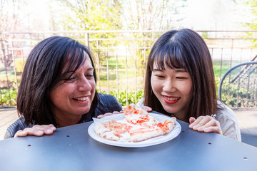 young multi-ethnic female friends watching a tasty pizza