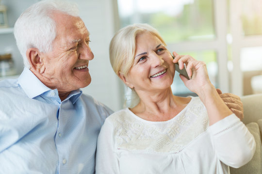 Senior couple talking on mobile phone at home