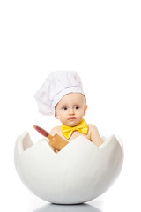 Portrait of a little adorable infant baby sitting in egg shell with dough rolling pin, isolated on a white background