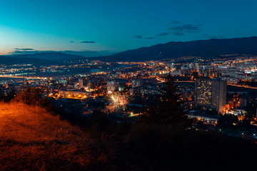 Fototapeta premium aerial view, night cityscape view with night sky. natural clear view with fireworks over big city blocks with street lights and hills around - Image