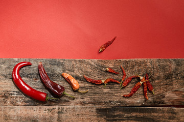 Dried chili pepper lying on wooden boards on a red background Image. Close up.