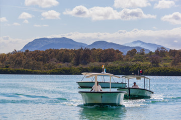 Touristic boats are ready to accept tourists in the bay of Mauritius island