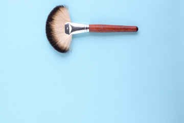 makeup brushes on a blue background. Top view, flat lay, copy space