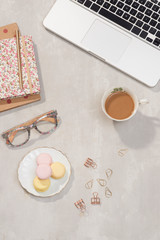 Workspace with laptop, notebook, glasses, cup of coffee and lisianthus flowers on gray background. Top view feminine office table desk. Freelancer working place