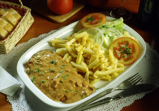 Bandeja con una escalopa de ternera rebozada, champi&ntilde;ones con salsa , ensalada y patatas fritas.