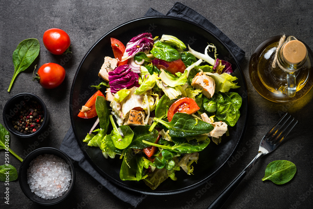 Canvas Prints green salad with chicken and vegetables on black.